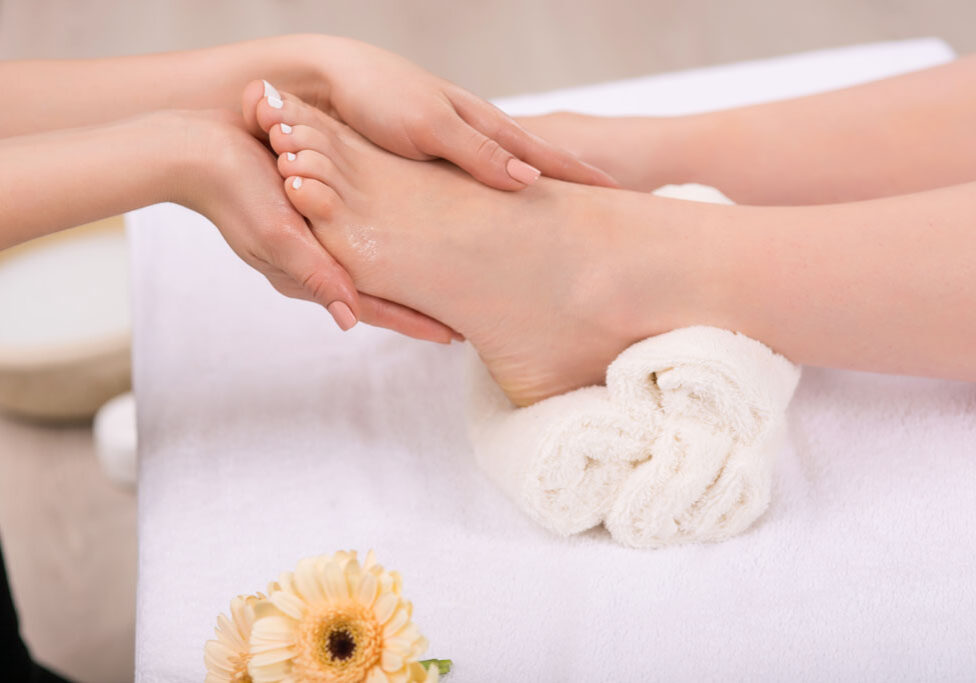 Receive satisfaction. Close up of hands of professional beautician holding feet of the client and massaging them while making  spa procedure